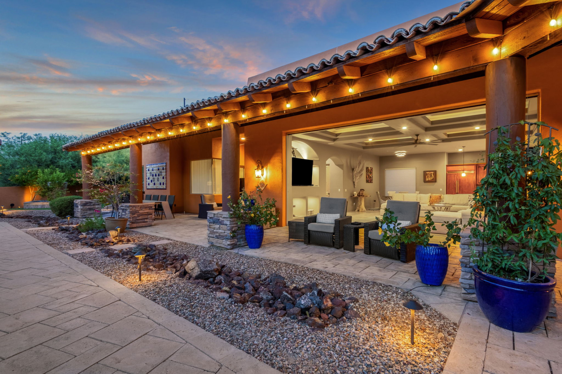 Covered patio with string lights opening to a great room at sunset