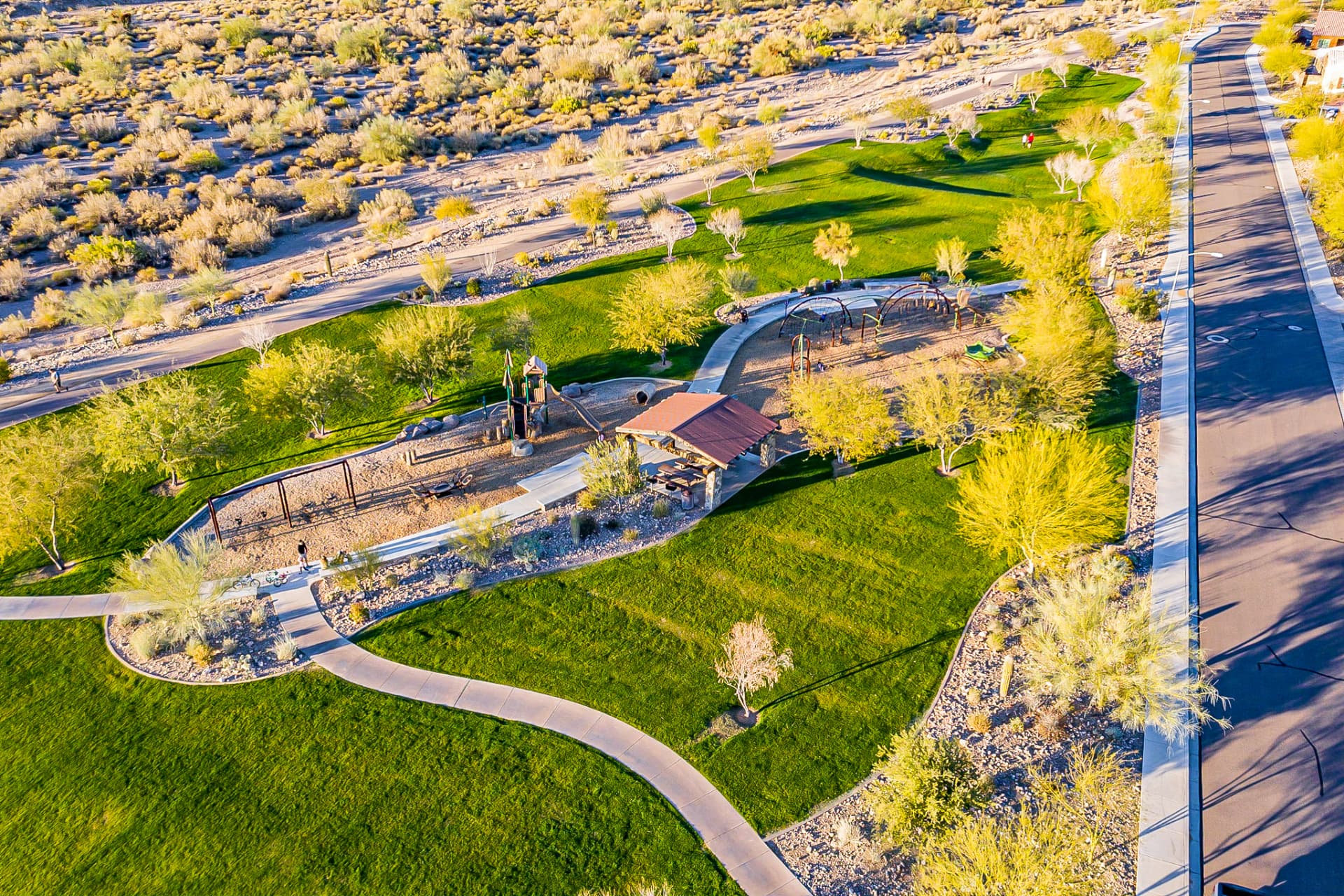 Aerial view of a Tierra Del Rio neighborhood park with playground, ramada, and walking paths at the desert edge
